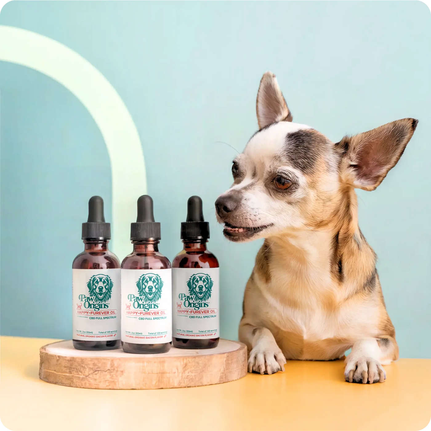 A small dog sits next to three bottles of pet supplement with droppers, displayed on a wooden platform against a pastel blue background.